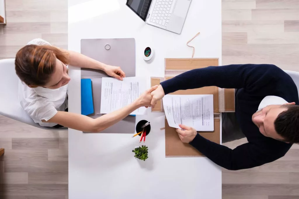 Two people shaking hands over a contract deal