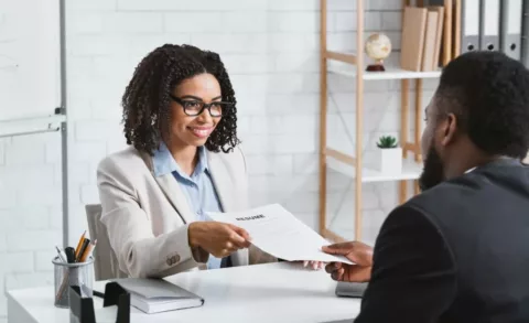 A woman giving her resume to the recruitment director in hopes to secure a position