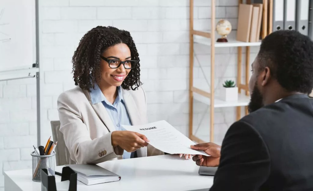 A woman giving her resume to the recruitment director in hopes to secure a position