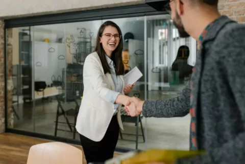 Woman meeting with new client smiling and shaking hands