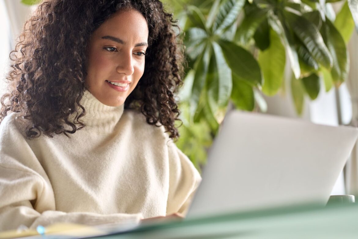 woman in white sweater searching on laptop