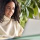 woman in white sweater searching on laptop